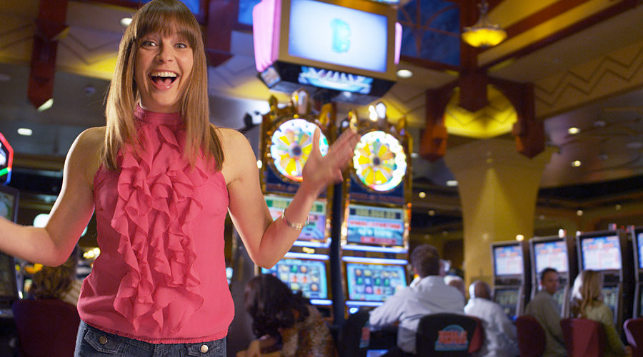 Woman cheering in front of Wheel of Fortune slot machine